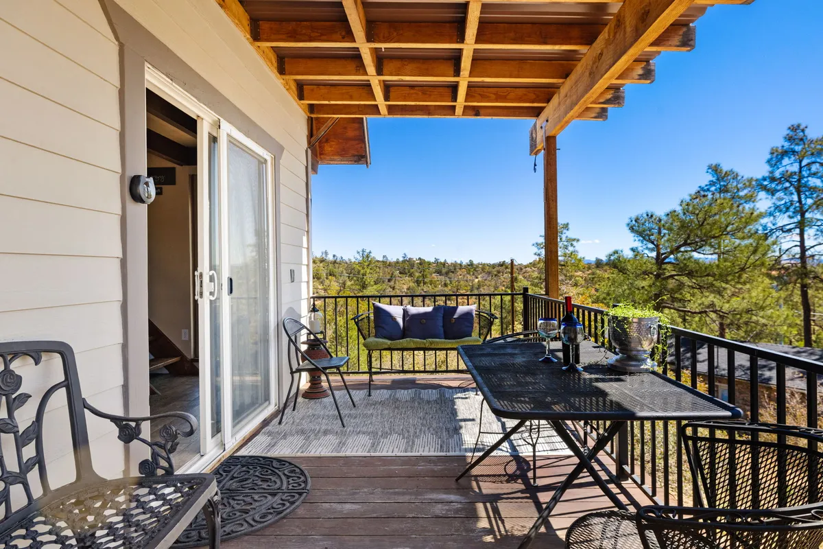 An inviting outdoor dining setup with comfortable furniture, positioned to enjoy views of the surrounding pine trees and nature. The peaceful ambiance suggests leisurely meals, quiet drinks, or unwinding in the fresh mountain air.