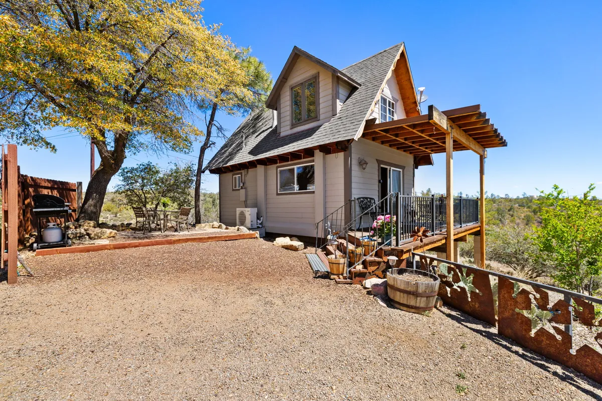 This image features a charming A-frame chalet with a spacious wooden deck surrounded by lush greenery. Decorative star accents add a cozy mountain touch, and the deck invites relaxation and outdoor meals while offering a direct connection to nature. The view hints at the tranquility of the mountain environment, making it ideal for enjoying coffee, grilling, or simply unwinding outdoors.