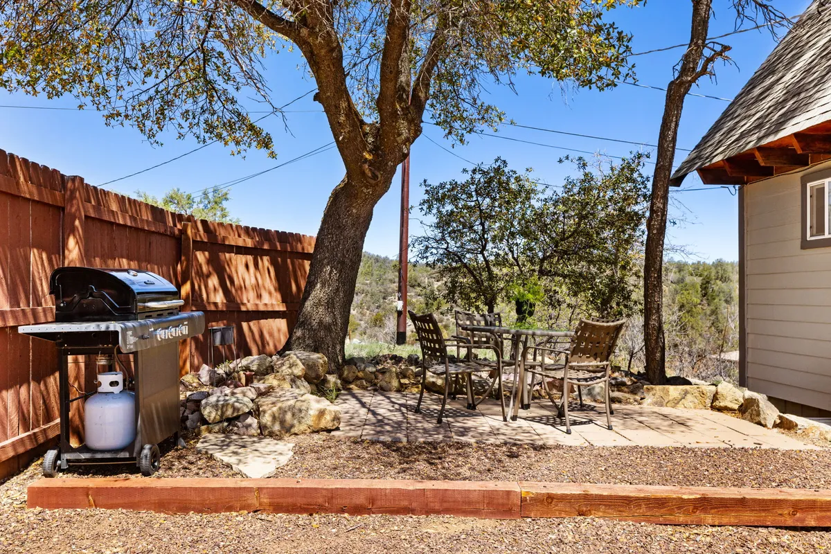 A cozy deck scene with a grill, dining table, and surrounding trees that immerse the space in nature. The inviting setup is ideal for barbecuing, sunset dinners, and starlit evenings, echoing the extension of indoor comfort to the outdoors. It captures the relaxed, communal vibe of grilling and socializing al fresco.